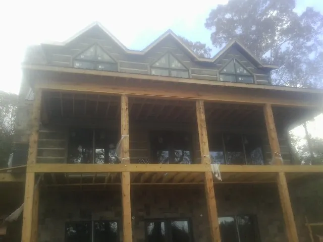 Dormers and porch framing on a large log home under construction — Roof Coating work by our crew in Wynnewood