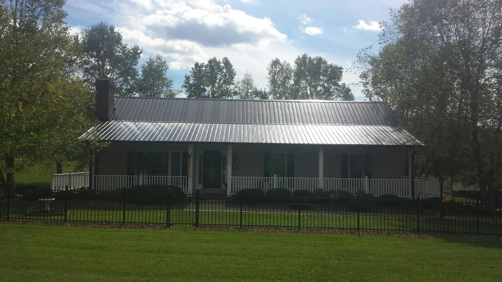 Gray metal roof on a brick ranch with a full width front porch — Gutter Guard Installation work by our crew in Wynnewood