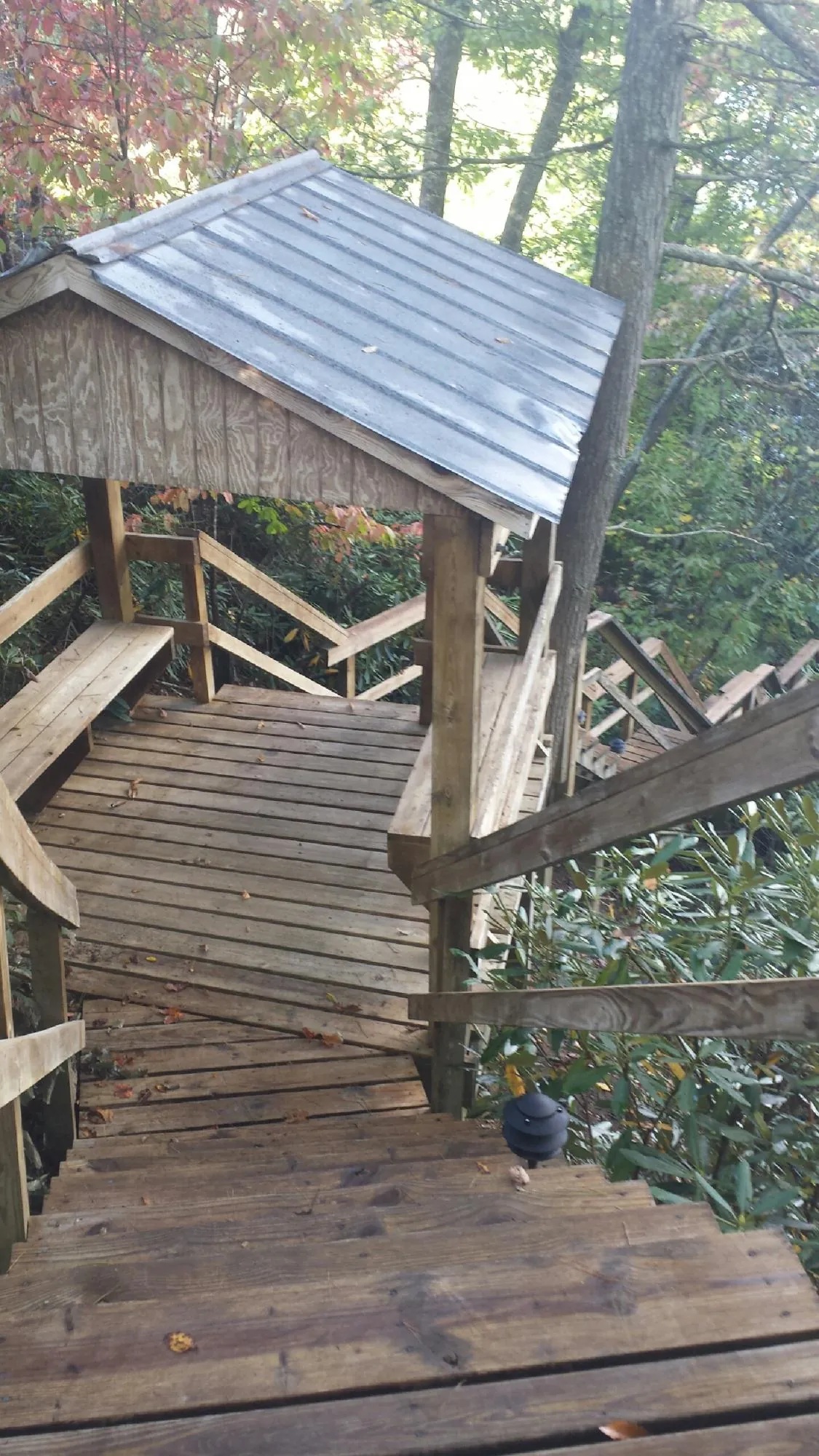 Metal roofed shelter over wooden steps on a wooded walkway — Skylight Repair & Installation work by our crew in Wynnewood